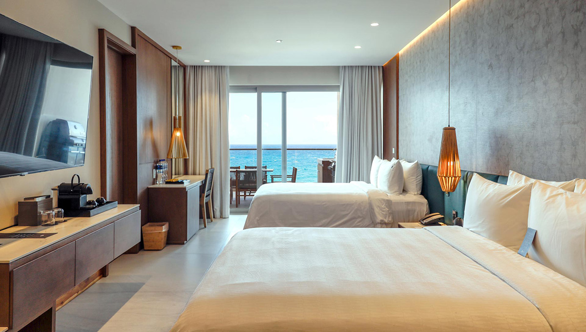 a room with two beds and a view of the ocean